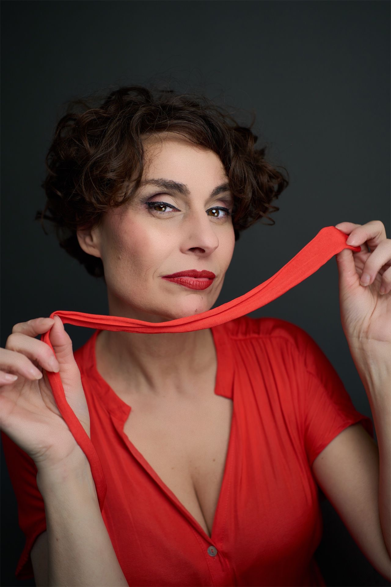 Begoña Álvarez con blusa roja y gesto expresivo sosteniendo una cinta